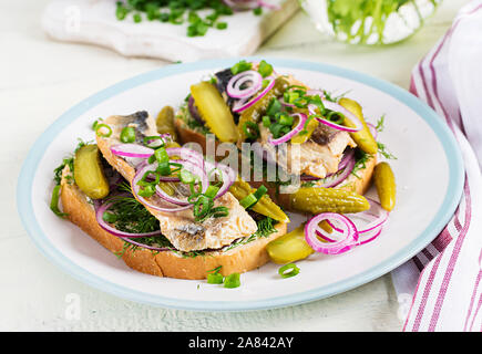 Sandwich hollandais traditionnel avec du hareng et des concombres cornichons sur tableau blanc. Smorrebrod. Banque D'Images