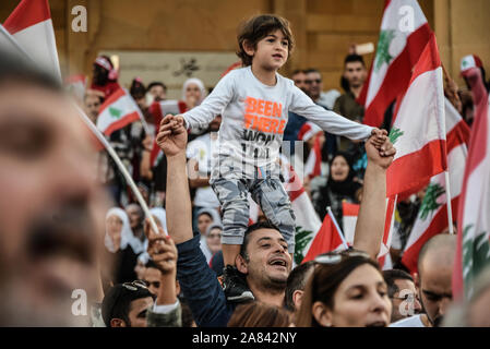 Un petit garçon se tient sur les épaules de son père pour obtenir une meilleure vue tout en protestant en place des martyrs, à Beyrouth. La population du Liban sont descendus dans les rues de nouveau dimanche, sur le 18e jour d'un soulèvement contre la corruption et la mauvaise gestion du gouvernement. Malgré sa démission le Premier Ministre Hariri, les manifestations continuent. Banque D'Images