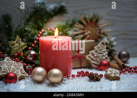 Arrangement de Noël avec une bougie allumée rouge, branches de sapin de Noël, et des ornements dans la neige contre un fond de bois sélectionné, l'accent, très nar Banque D'Images
