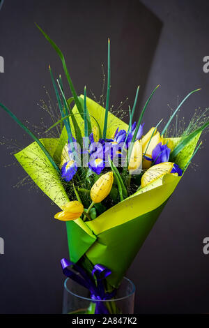 Tulipes jaune et violet iris, bouquet de fleurs dans un bel emballage dans un vase de verre. Carte de souhaits pour toutes les occasions, en particulier au printemps. Romantic Banque D'Images