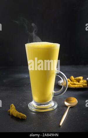 Verre de lait latte golden ayurvédique curcuma curcuma poudre, avec plus de table noire. Tir vertical. Banque D'Images