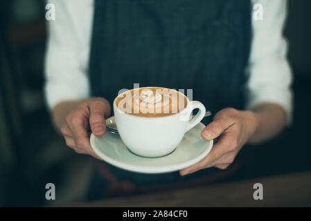 Barista holding Coffee cup avec latte art, télévision, pas de tête blanc Banque D'Images