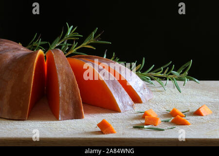 Libre de tranches de potiron avec le romarin sur table en bois. Des légumes crus. Banque D'Images