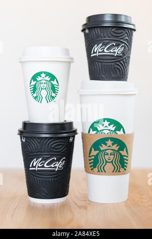 KIEV, UKRAINE / Novembre 06, 2019 : quatre tasses de café Starbucks et McDonald's café sur table en bois sur fond clair. La confrontation de la marque Banque D'Images