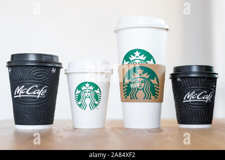 KIEV, UKRAINE / Novembre 06, 2019 : quatre tasses de café Starbucks et McDonald's café sur table en bois sur fond clair. La confrontation de la marque Banque D'Images