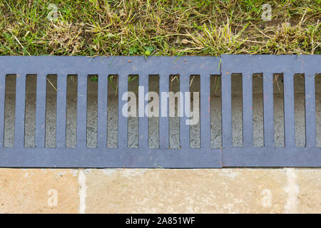 Close-up de gouttière d'évacuation d'eau qui sépare la pelouse de la terrasse pavée - flatlay Banque D'Images