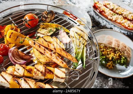 Caillé ou butternut et halloumi cuisson brochettes sur un barbecue d'hiver dans la neige avec des poivrons, fenouil, carottes, tomates, courges et mushr Banque D'Images