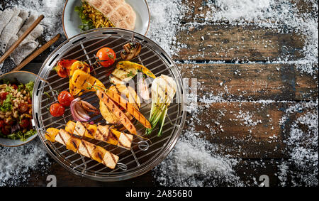 Un assortiment de légumes frais de la ferme grillées sur un barbecue en plein air en hiver neige avec halloumi ou caillé de brochettes pour un régime végétarien sain Banque D'Images