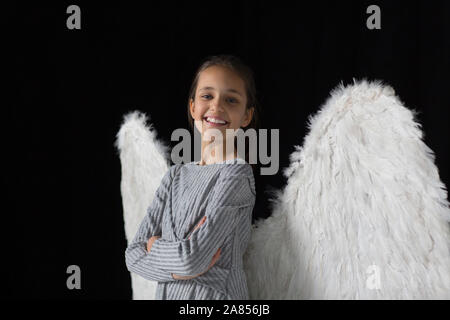 Portrait souriant, confiant girl wearing angel wings Banque D'Images