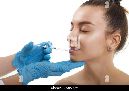 La beauté du visage injections. Portrait belle jeune femme recevant l'injection d'acide hyaluronique. Closeup Of Hands Holding Gants en seringue à proximité Banque D'Images