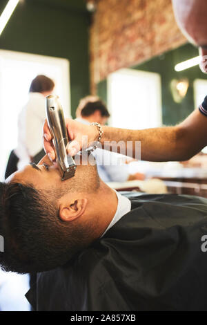 Coiffure homme visage rasage de client dans un salon de barbier Banque D'Images