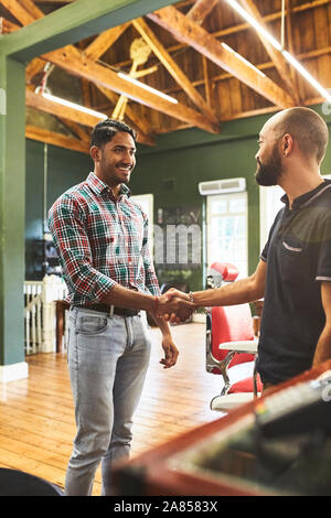 Salon de coiffure masculin et le client shaking hands in barbershop Banque D'Images