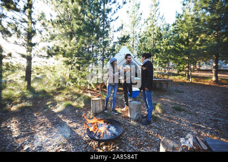 Les amis de boire du vin de camping dans les bois Banque D'Images