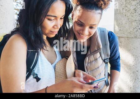 Les jeunes femmes des amis à l'aide de smart phone Banque D'Images