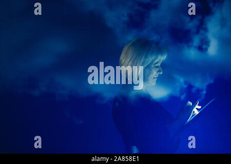 Double exposition businesswoman with digital tablet against blue sky with clouds Banque D'Images