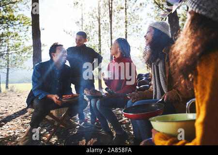 La famille et les amis de manger au soleil camping dans les bois Banque D'Images