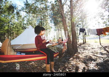 Père et fille en hamac de camping dans les bois Banque D'Images