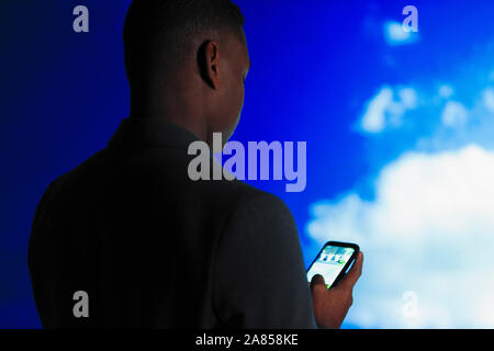 Double exposition businessman using smart phone contre ciel bleu avec des nuages Banque D'Images