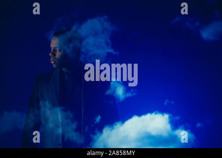 Double exposition businessman looking away against blue sky with clouds Banque D'Images