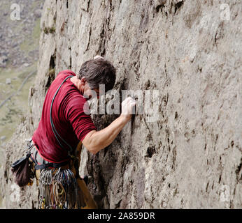 Male rock climber scaling rock face Banque D'Images