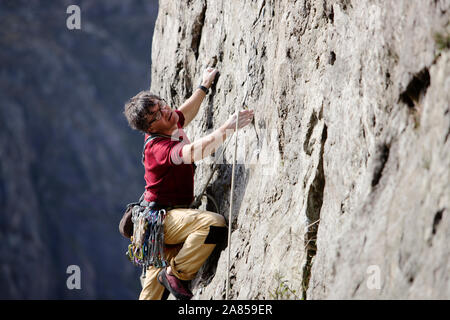 Male rock climber scaling rock face Banque D'Images