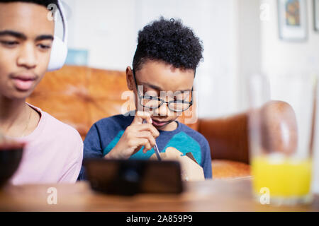 Frères et de manger à l'aide de smart phone Banque D'Images