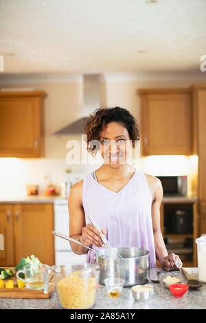 Portrait souriant, confiant woman cooking in kitchen Banque D'Images