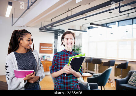 Smiling businesswomen walking and talking in office Banque D'Images