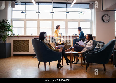 Businesswomen talking in open plan office Banque D'Images