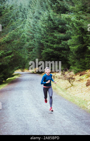 Woman running sur le sentier en forêt à distance Banque D'Images