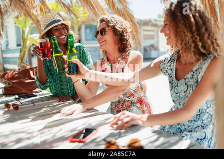 Happy women friends drinking cocktails et de la bière au bar de plage ensoleillée Banque D'Images