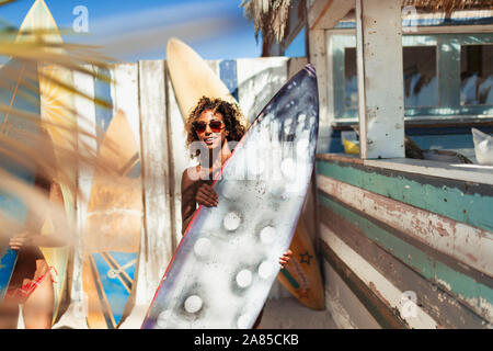 Portrait young woman with surfboard on sunny beach Banque D'Images