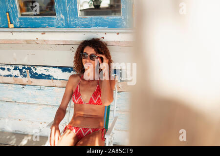 Young woman in bikini relaxing on beach hut patio Banque D'Images