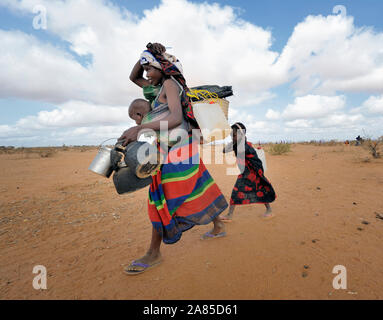 Une mère et ses enfants--réfugiés nouvellement arrivés--porter leurs biens à travers le camp de Dadaab dans le nord-est du Kenya. Banque D'Images