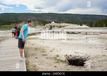 L'homme regarde vers le bas un trou sombre printemps volcaniques dans la partie supérieure du bassin du geyser Banque D'Images