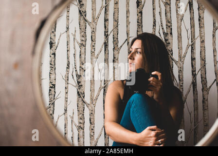 Femme tenant en tenant l'appareil photo de son reflet dans le miroir. Banque D'Images