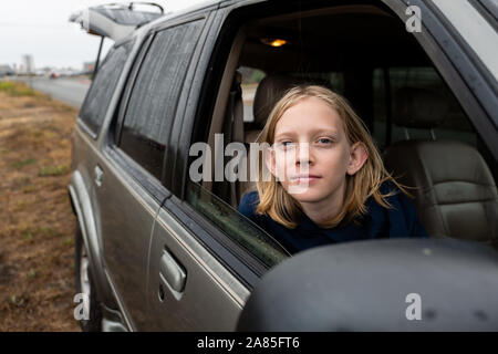 Le Tween looking at camera de siège passager de SUV Banque D'Images