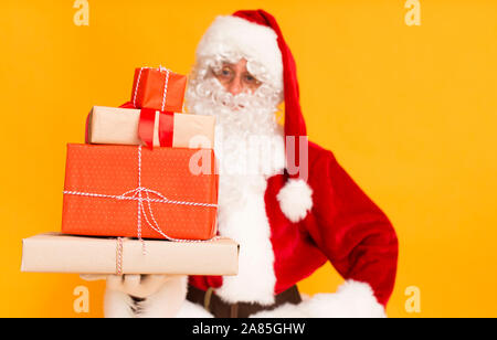 Cadeaux de Noël enveloppé dans du papier de couleur Santa holding sur orange Banque D'Images