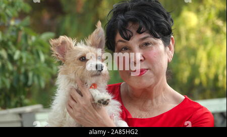 Hispanic woman dans ses années 60, tenant son petit chien mignon Banque D'Images