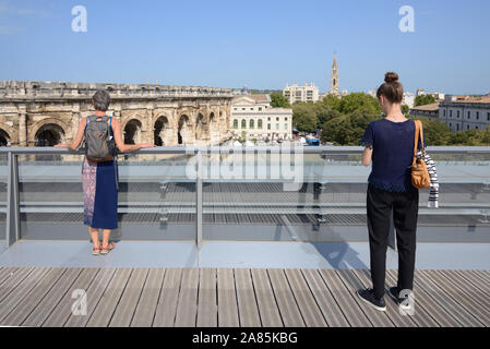 Les touristes profitant de la vue depuis le toit-terrasse du Musée de la Romanité, ou Musée romain, sur l'Amphithéâtre romain ou Arène de Nimes France Banque D'Images