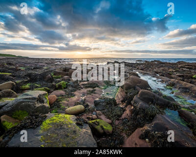 La côte sauvage de John O'Groats dans le nord de l'Écosse sur un coucher du soleil sombre soir avec l'île de stroma visible dans la distance. Banque D'Images