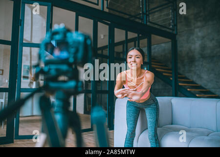 Blogger faisant des exercices de remise en forme souriant en face de l'appareil photo Banque D'Images