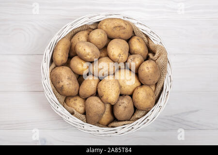 Sur les pommes de terre crues panier rustique sur fond blanc. Vue d'en haut. Solanum tuberosum Banque D'Images