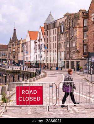 Woman crossing road route fermée par signe, la rive, Leith, Edinburgh, Ecosse, Royaume-Uni Banque D'Images