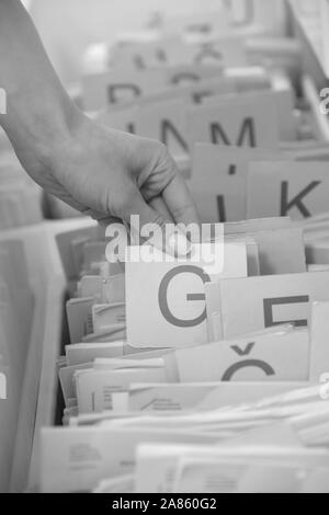 Les mains d'une femme de choisir un dossier médical dans le registre de la clinique Banque D'Images