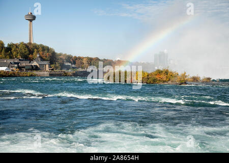 Vue vers le bas de la rivière Niagara à l'égard des chutes canadiennes montrant un arc-en-ciel au-dessus des chutes et de la tour Skylon dans l'arrière-plan Banque D'Images