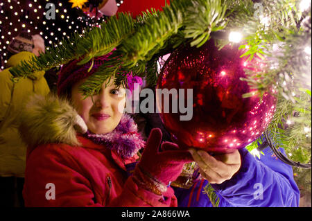 Jeune fille de toucher une boule de noël à la cathédrale de Cologne Marché de Noël Banque D'Images