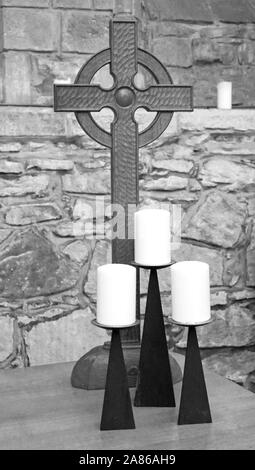 Une nature morte en monochrome d'une croix et trois bougies dans la Cathédrale de Dornoch, Sutherland, Scotland, Royaume-Uni, Europe. Banque D'Images