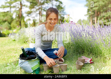 Femme de plantation des graines à des pots de jardin d'été Banque D'Images