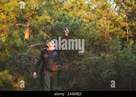 Recherche homme randonneur signal pour téléphone mobile pendant la randonnée en forêt d'automne Banque D'Images